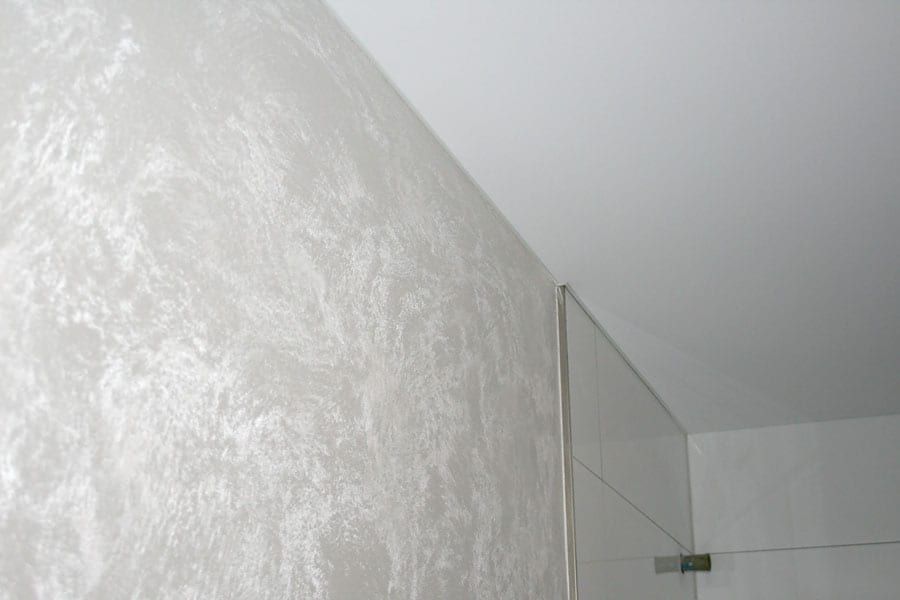 Badezimmergestaltung mit einer Spanndecke. Wände mit einer metallischen Lasur und Kristallzugabe veredelt