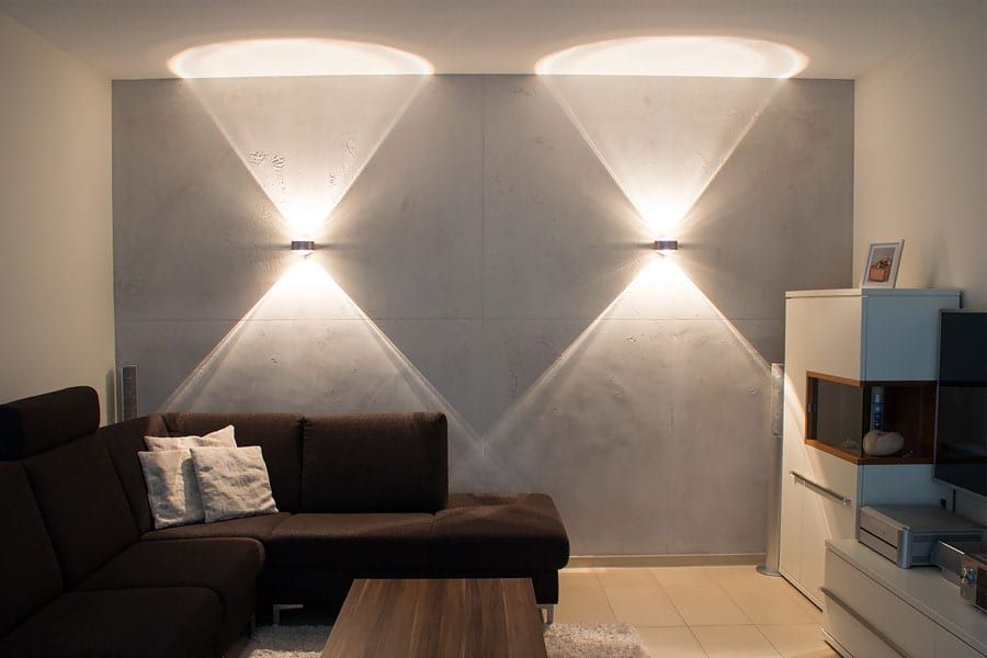 Akzentbeleuchtung auf einer Betonoptik-Wand erzeugt dramatische Lichtkegel.