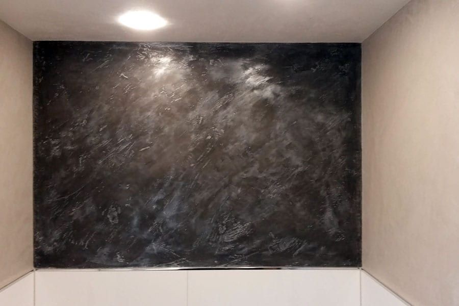 Calce Colino im Badezimmer schwarz mit silber veredelt. Restliche Wände und Decke in weiß. Diffusionsoffen auf Kalkbasis. Einprägung von echtem Bambus in Calce Colino mit fossil versteinerter Wirkung.
