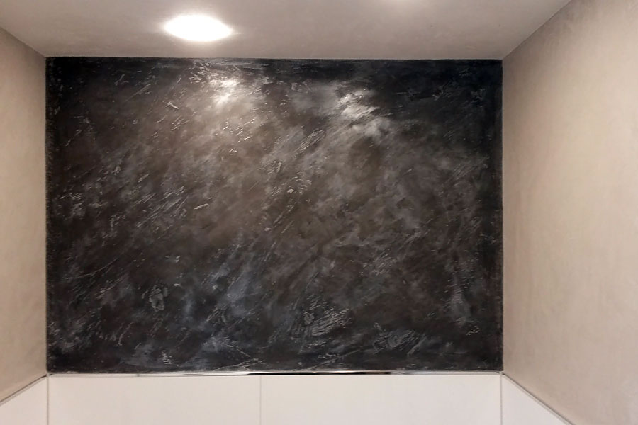 Calce Colino im Badezimmer schwarz mit silber veredelt. Restliche Wände und Decke in weiß. Diffusionsoffen auf Kalkbasis. Einprägung von echtem Bambus in Calce Colino mit fossil versteinerter Wirkung.