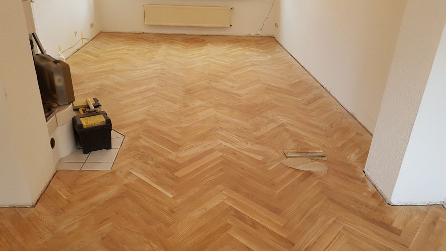 Eiche massiv Parkett, 22mm stark, im Fischgrat Verband verlegt und endbehandelt. Inkl. Fußleistenmontage.