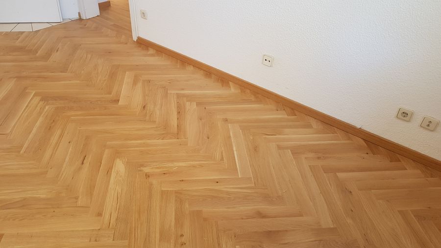 Eiche massiv Parkett, 22mm stark, im Fischgrat Verband verlegt und endbehandelt. Inkl. Fußleistenmontage.