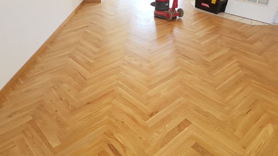 Eiche massiv Parkett, 22mm stark, im Fischgrat Verband verlegt und endbehandelt. Inkl. Fußleistenmontage.