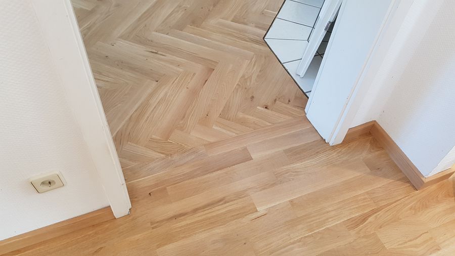 Eiche massiv Parkett, 22mm stark, im Fischgrat Verband verlegt und endbehandelt. Inkl. Fußleistenmontage.