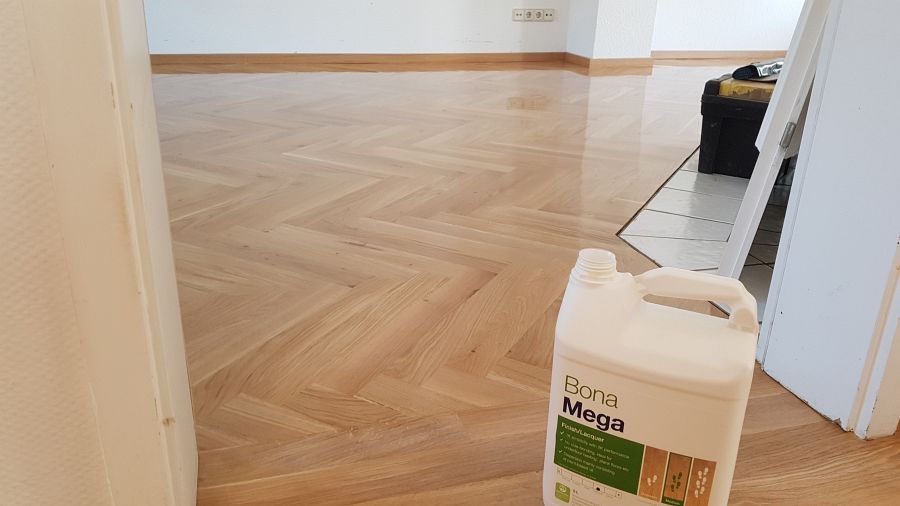 Eiche massiv Parkett, 22mm stark, im Fischgrat Verband verlegt und endbehandelt. Inkl. Fußleistenmontage.