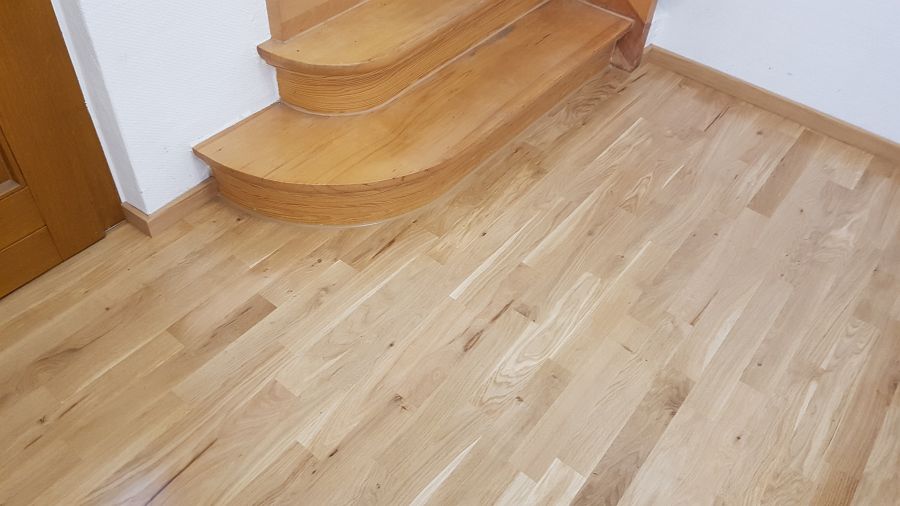 Eiche massiv Parkett, 22mm stark, im Fischgrat Verband verlegt und endbehandelt. Inkl. Fußleistenmontage.