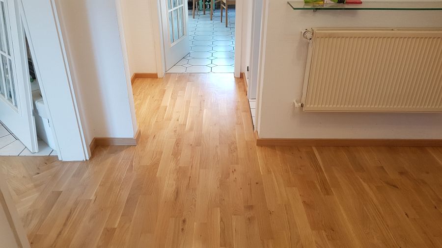 Eiche massiv Parkett, 22mm stark, im Fischgrat Verband verlegt und endbehandelt. Inkl. Fußleistenmontage.