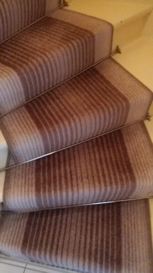 Treppenläufer auf einer Holztreppe verlegt und die gewendelten Stufen fachmännisch eingenäht